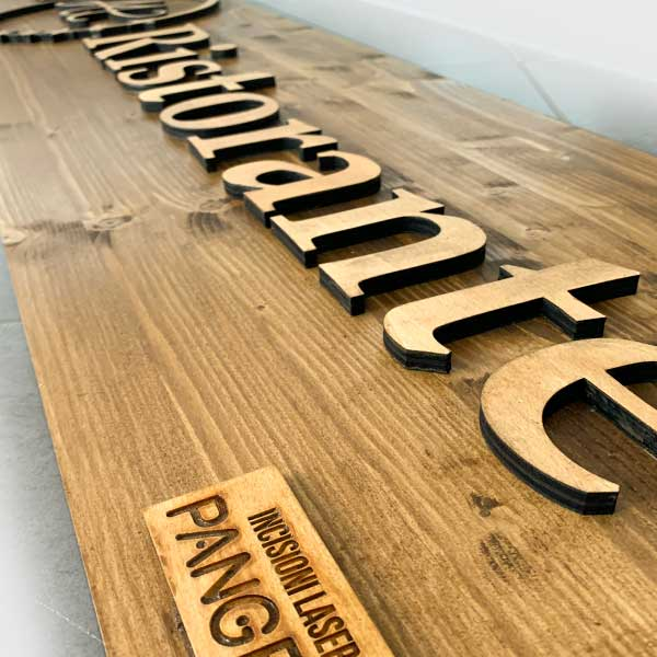 Dettaglio di lettere a rilievo su pannello in legno lavorato al laser