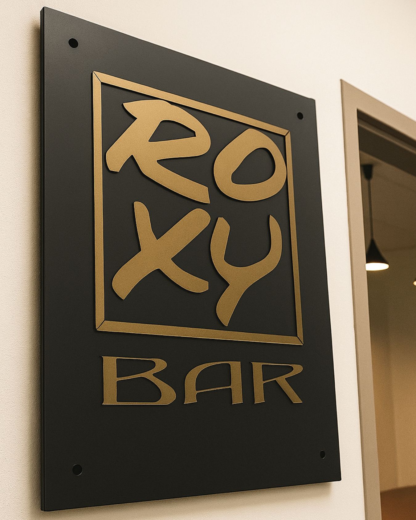 Insegna Roxy Bar a Montù Beccaria con base in plexiglass nero opaco e lettere in acrilico oro opaco a rilievo
