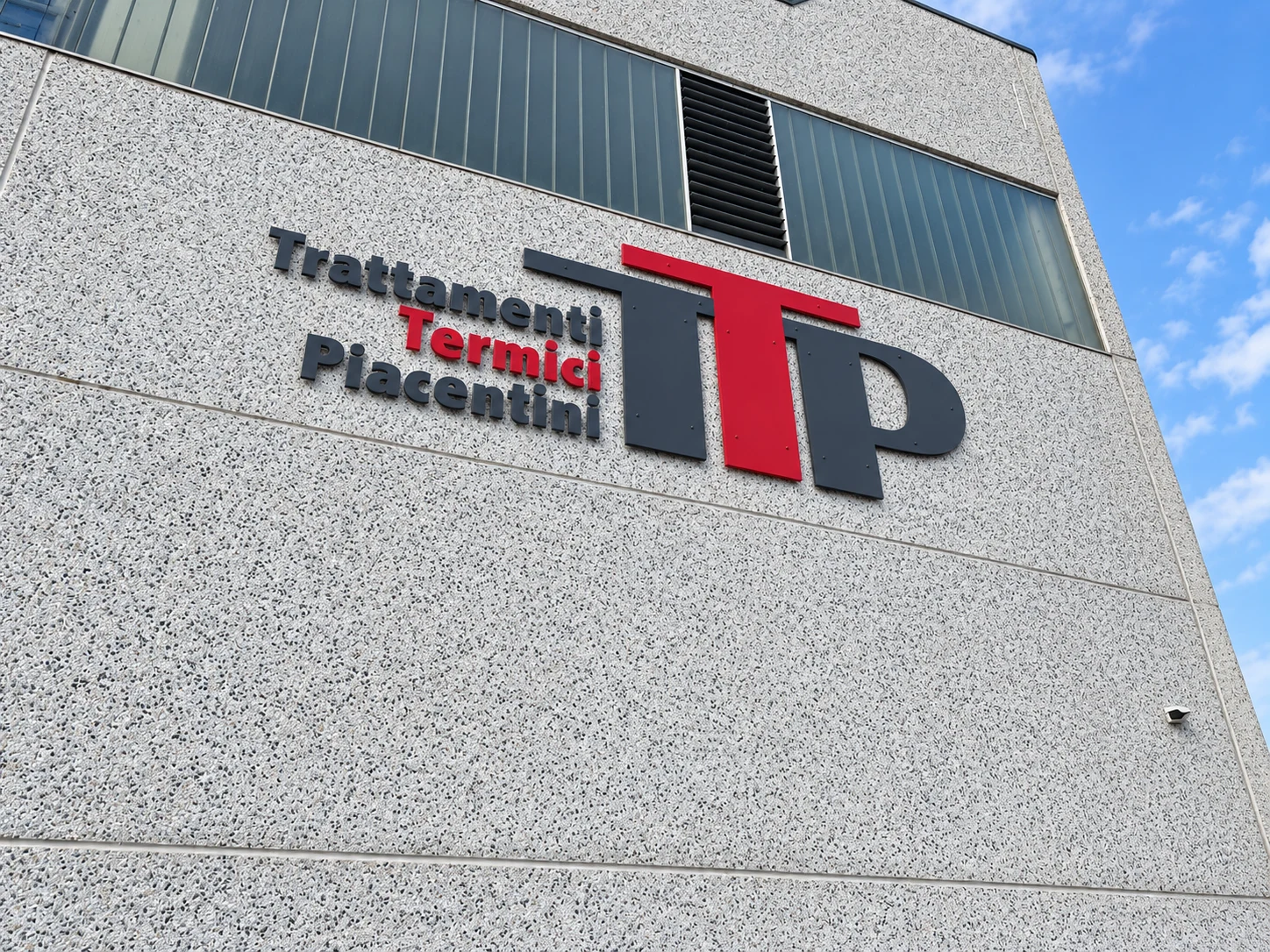 Insegna TTP con lettere rosse e antracite sulla facciata dello stabilimento