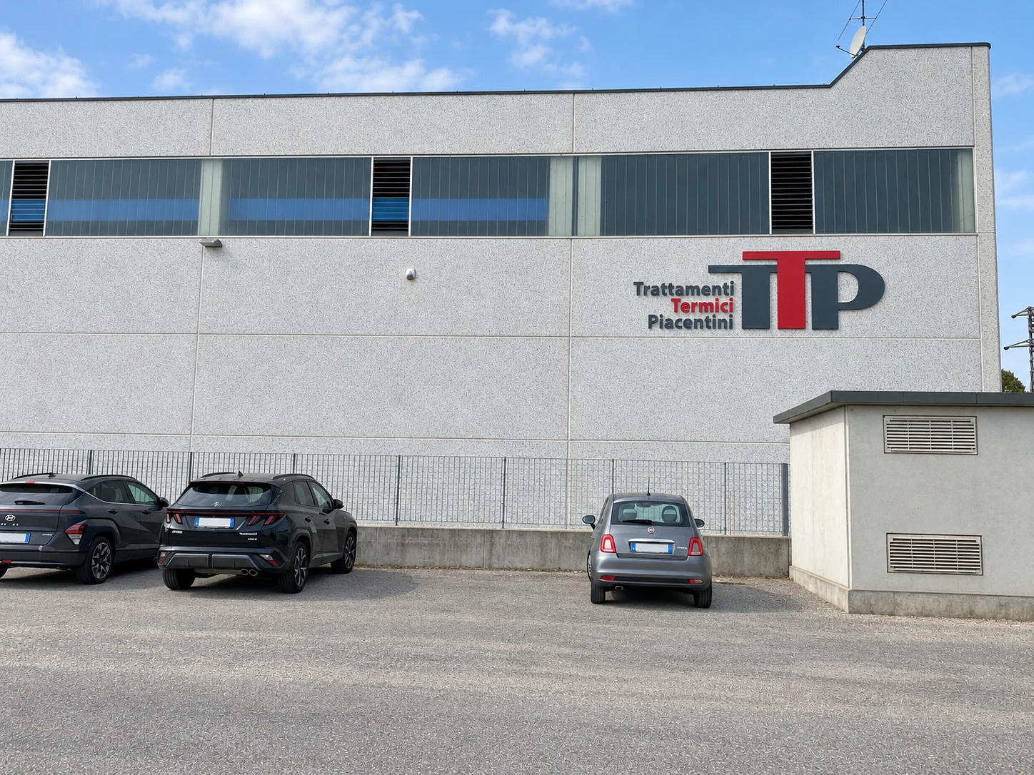 Vista larga dello stabilimento TTP con l’insegna sulla facciata e il parcheggio